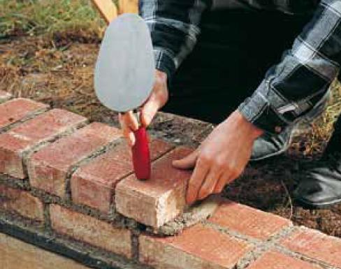 Faire de même pour la brique suivante et ne pas oublier d’appliquer aussi du mortier sur la face verticale de la première brique. Serrer la brique dans le lit de mortier. L’amener à sa position définitive et parallèle au cordeau, en la frappant avec le manche de la truelle. Pour les rangées suivantes, respecter le tracé des joints